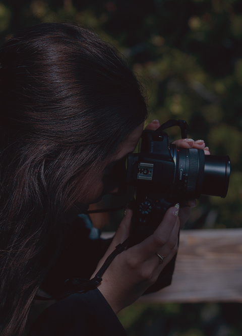 Side profile of woman holding a camera and looking through the view finder